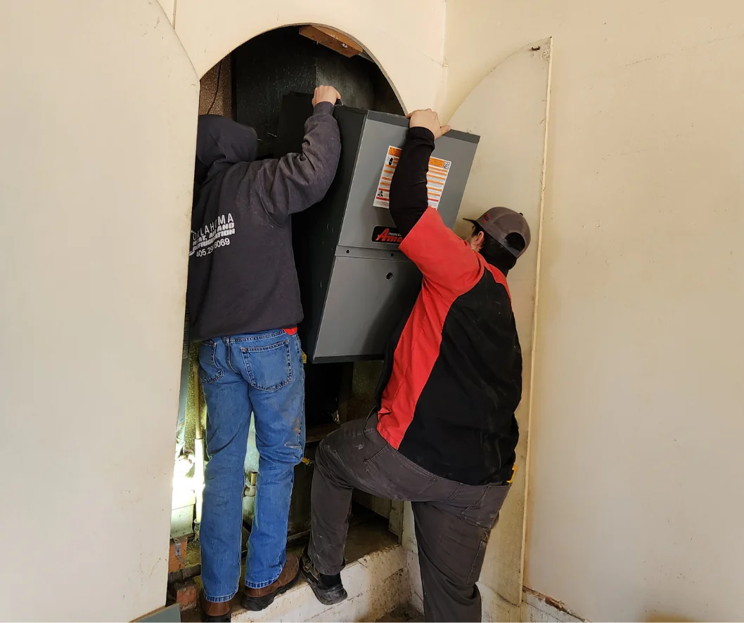 Technicians installing indoor HVAC equipment